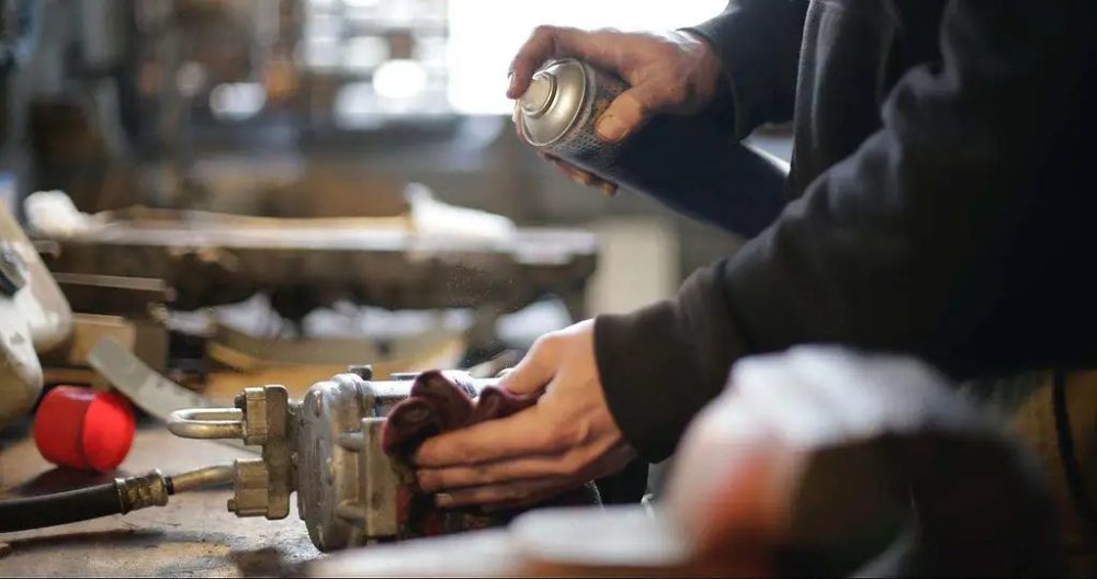 a man cleaning metal with silicone spray